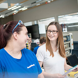 Zwei weibliche Auszubildende stehen in einem Ausbildungsraum und führen ein Gespräch