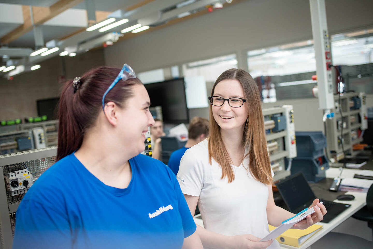 Zwei weibliche Auszubildende stehen in einem Ausbildungsraum und führen ein Gespräch